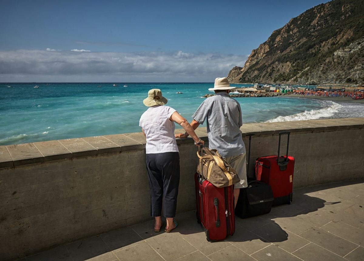 A couple with their suitcases taking in a turquoise bay